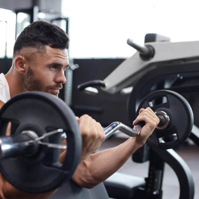 Mann trainiert mit der Hantel im Fitnessstudio